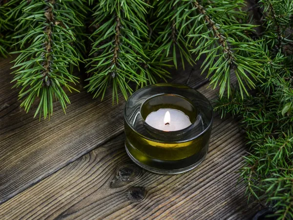 Blick auf einen Holztisch mit brennendem Teelicht und Tannengrün